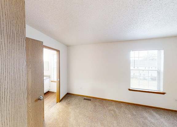 A room with a carpeted floor and a window.