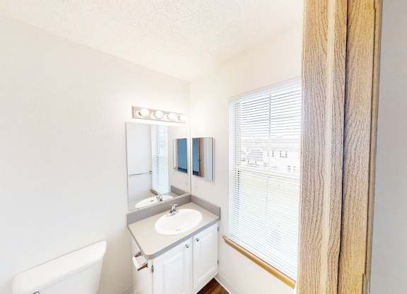 A white bathroom with a sink, mirror, and towel rack.