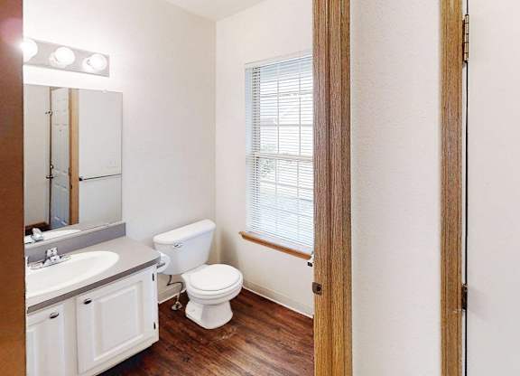 A white toilet sits in a bathroom next to a sink and a mirror.