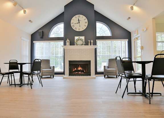 the gathering place at gardner village community room with fireplace and tables and chairs