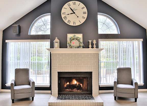 Clubhouse with two chairs and a fireplace with a large clock on the wall