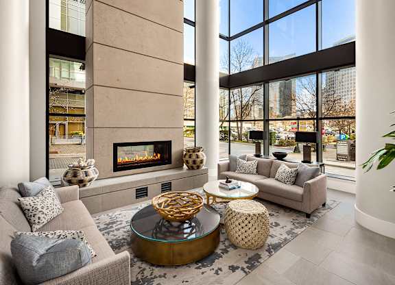 a living room with couches and a fireplace in front of tall windows at Two Lincoln Tower, Bellevue, 98004