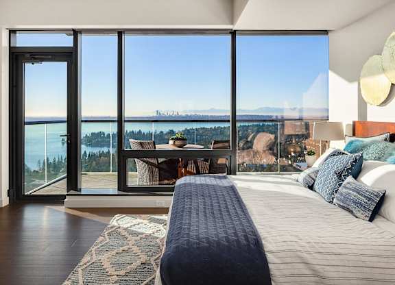 a bedroom with a bed and a view of the water and mountains at Two Lincoln Tower, Bellevue, WA, 98004