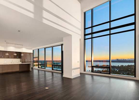 an open living room with a view of the water and sunset at Two Lincoln Tower, Bellevue, WA, 98004