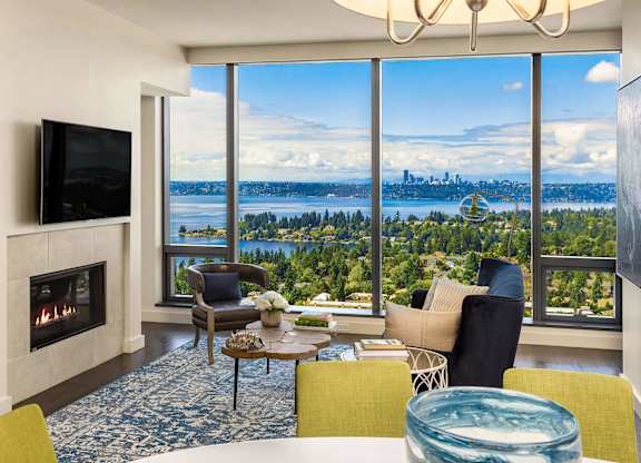 a living room with a fireplace and a view of a city and a lake at Two Lincoln Tower, Bellevue