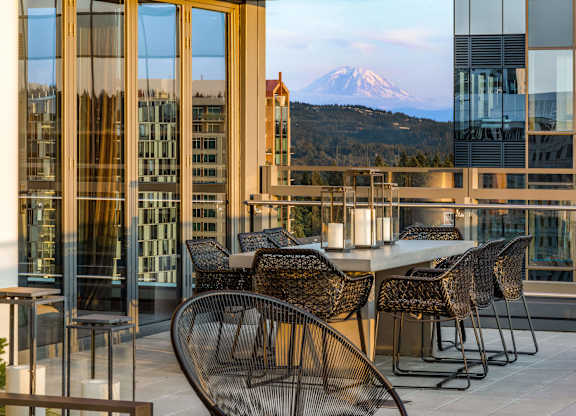 a table and chairs on a balcony with a view of a mountain at Two Lincoln Tower, Bellevue, WA, 98004
