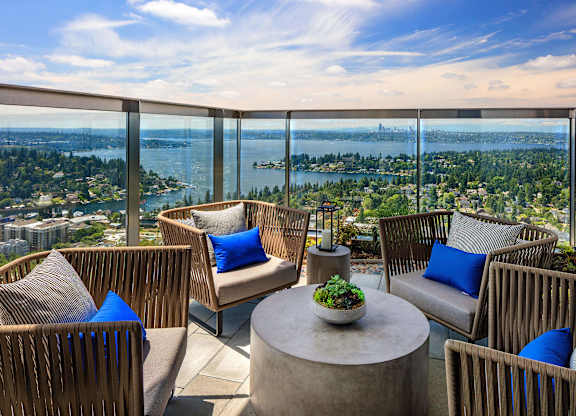 a balcony with chairs and a table and a view of a city and the water at Two Lincoln Tower, Bellevue, WA, 98004