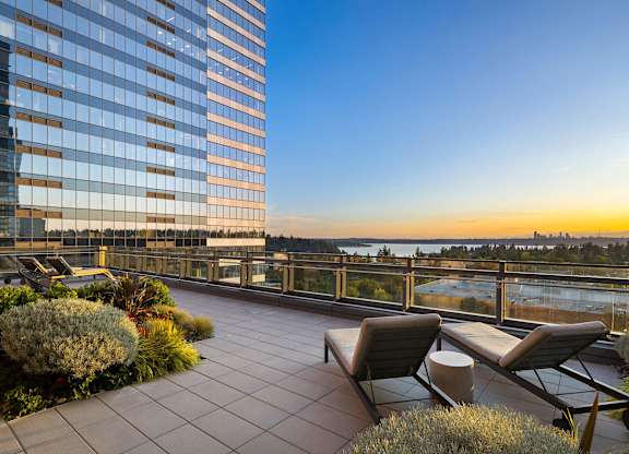 a terrace with chairs and a table overlooking the water and a tall building at Two Lincoln Tower, Bellevue, WA, 98004