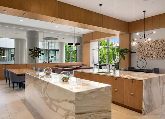 A modern kitchen with a marble island and wooden cabinets.