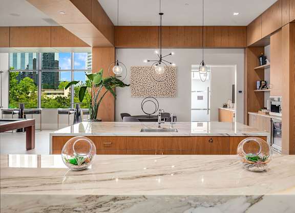 A modern kitchen with a marble countertop and wooden cabinets.