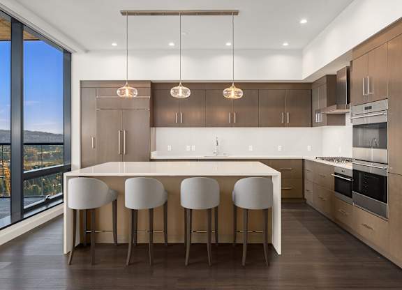 A modern kitchen with a large island and bar stools at Two Lincoln Tower, Bellevue, WA.
