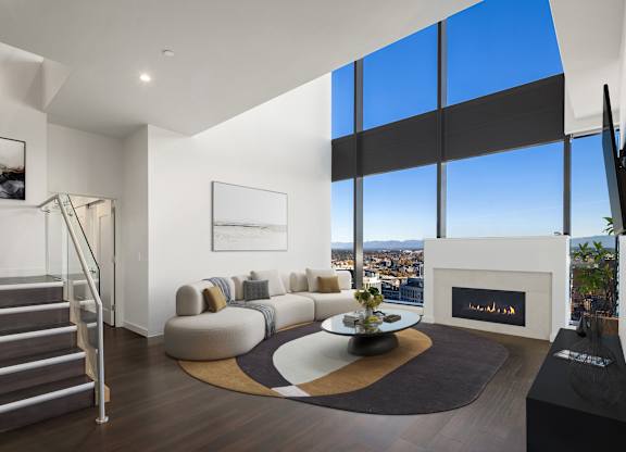 A modern living room with a staircase and a fireplace in the penthouse at Two Lincoln Tower, Bellevue, WA 98004.
