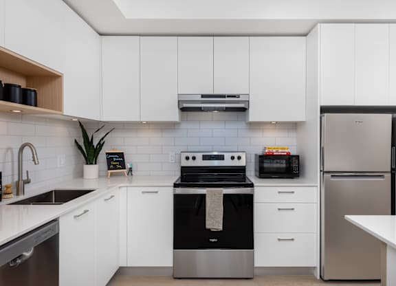 A modern kitchen with white cabinets and stainless steel appliances.