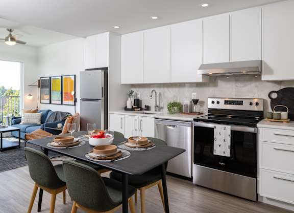 A modern kitchen with a dining table set for two.