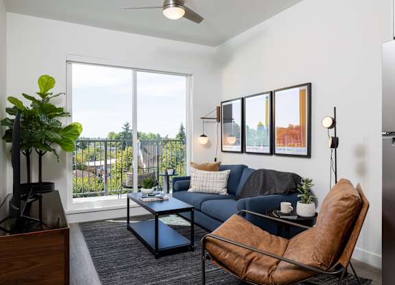 A living room with a couch, chair, and a potted plant.