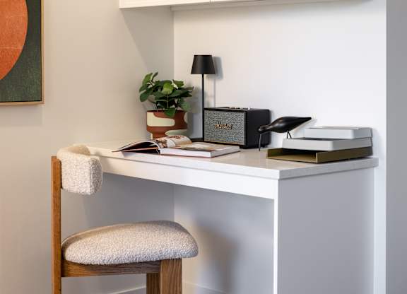 A white desk with a chair and a potted plant.