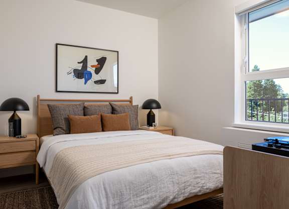 A bedroom with a large bed and a painting above it.