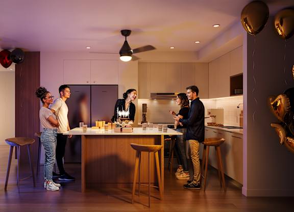 A group of people are gathered around a kitchen island.