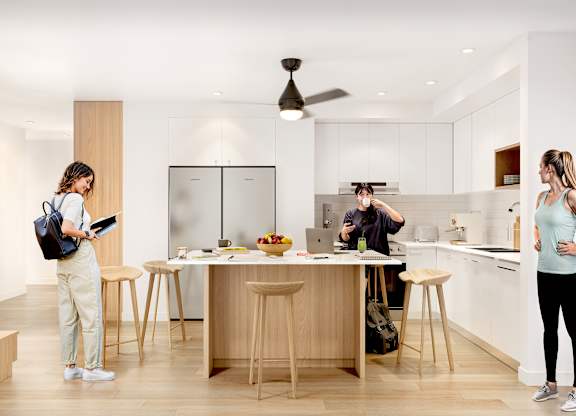Three people are standing in a modern kitchen.