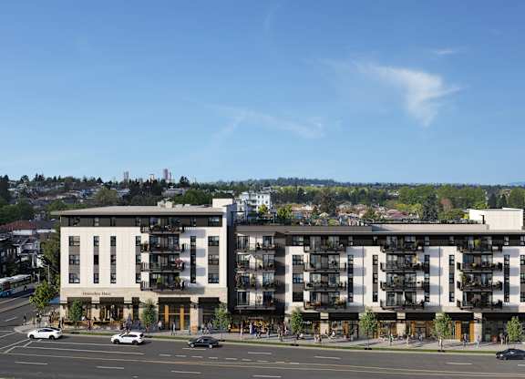 Two modern apartment buildings are situated on a street corner with cars parked in front.