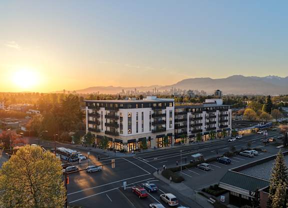 A sunset view of a city street with cars and buildings.
