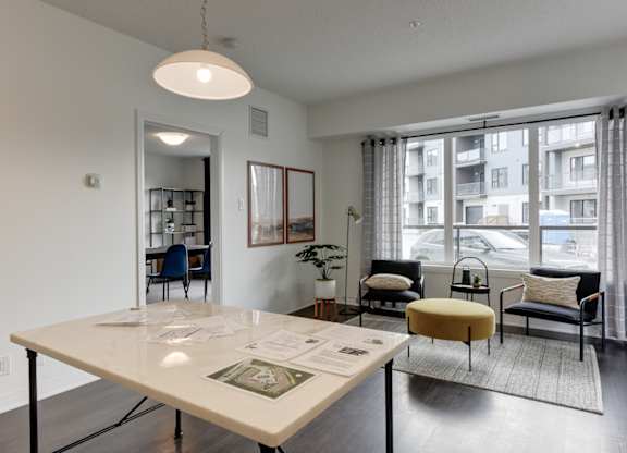 A white table with papers on it is in a room with a view of a balcony.