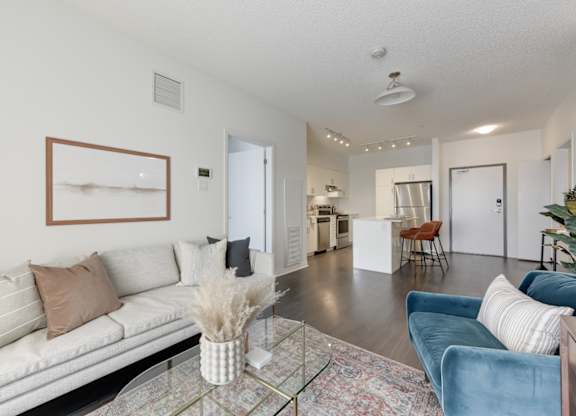 A living room with a white couch and a glass coffee table.