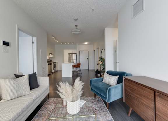 A living room with a white couch, a blue chair, and a wooden cabinet.