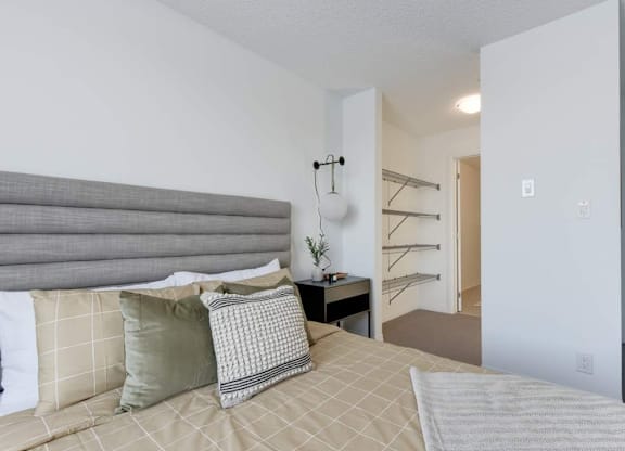 A bedroom with a bed, pillows, and a lamp.