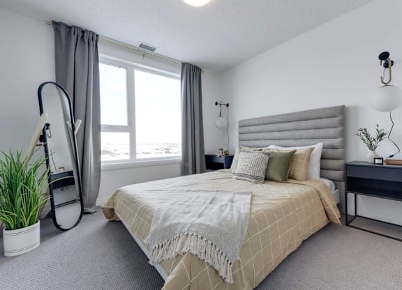 A bedroom with a large bed and a window with curtains.