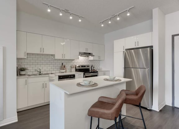 A modern kitchen with white cabinets and a white island.