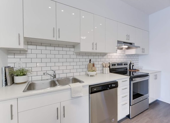 A modern kitchen with white cabinets and stainless steel appliances.