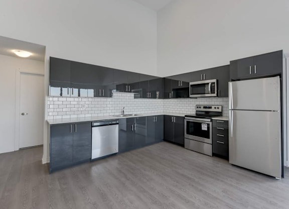 A modern kitchen with stainless steel appliances and a white subway tile backsplash.