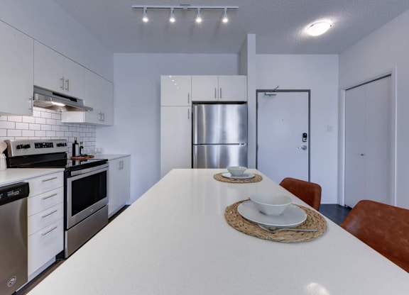 A modern kitchen with a white countertop and stainless steel appliances.