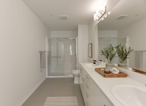 A white bathroom with a glass shower door and a white sink.