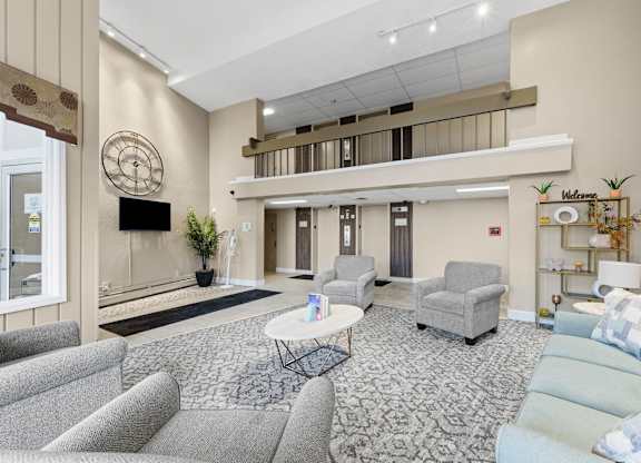 A living room with a grey sofa, a white coffee table, and a television on the wall.