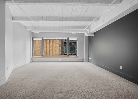 A large, empty room with a window covered in blinds.