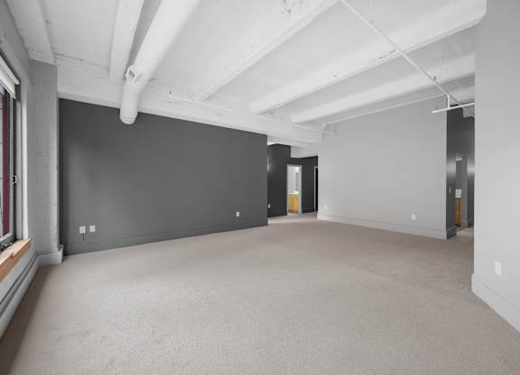 A large, empty room with white walls and carpeted floor.