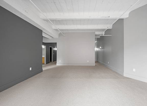 A large, empty room with grey walls and a carpeted floor.