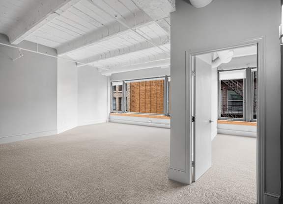 A room with a carpeted floor and a doorway leading to another room.