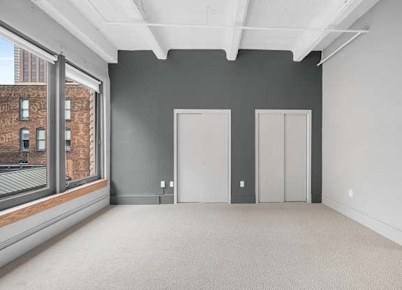 A large empty room with grey walls and carpeted floor.