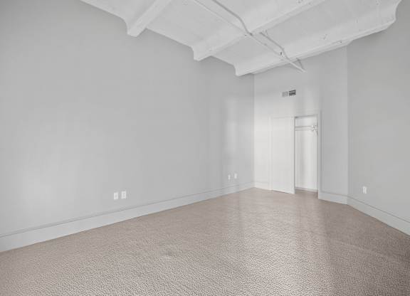 A large empty room with carpeted floor and white walls.