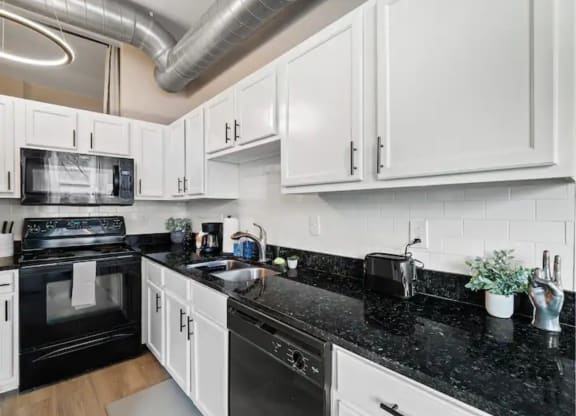 a kitchen with white cabinets and black counter tops