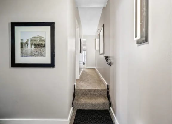 a long hallway with a picture hanging on the wall and a runner on the floor