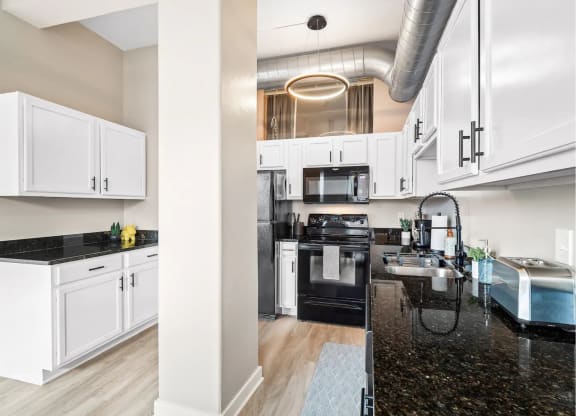 a kitchen with white cabinets and black counter tops