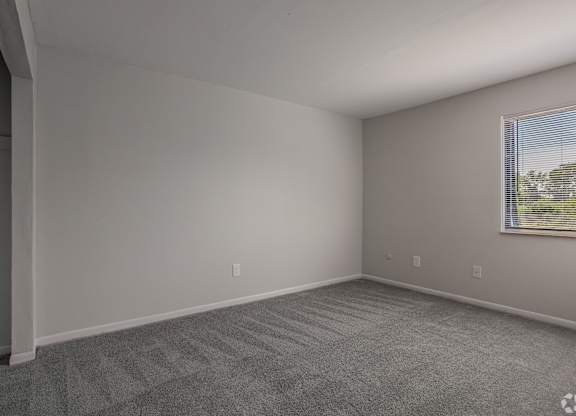 A room with a carpeted floor and a window with blinds at Commons At Waters Edge, Columbus Ohio