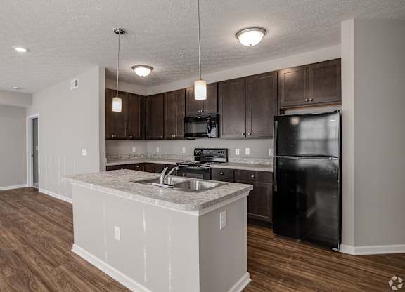A kitchen with a black refrigerator and wooden cabinets.at The Residences at Akita Lane, Ohio, 43110