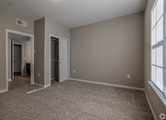 A room with a carpeted floor and two doors leading to other rooms.at The Residences at Akita Lane, Canal Winchester, OH 43110