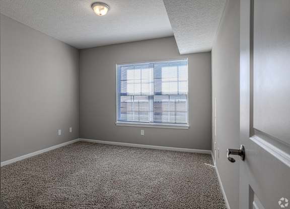 A room with a carpeted floor and a window with blinds.at The Residences at Akita Lane, Canal Winchester, OH 43110