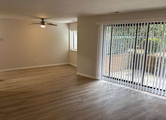 A room with a ceiling fan and sliding glass doors.